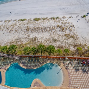 Enjoy the inviting gradual entry pool area with a waterslide, surrounded by lush palm trees and easy beach access