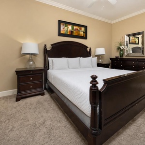 This guest bedroom features a dark wood king bed, stylish lamps, and a mirror, creating a serene and restful atmosphere