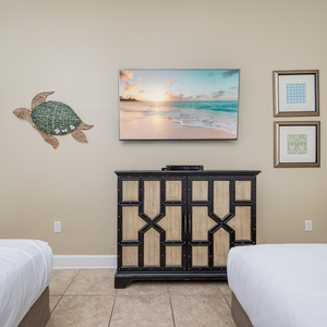 Enjoy the coastal decor and relaxing vibe in this inviting guest bedroom with two queen beds and a large TV