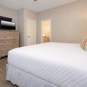 Cozy guest bedroom featuring a plush king bed, stylish decor, and a wall-mounted TV