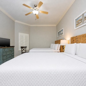 This guest bedroom features two comfortable queen beds, a flat-screen TV, and coastal decor for a relaxing stay