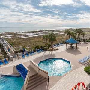 Enjoy the inviting pool area with lounge chairs and a scenic boardwalk leading to the beach just steps away