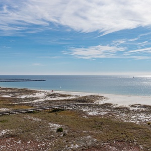Expansive view of the tranquil beach, showcasing soft white sand and gentle waves under a clear blue sky