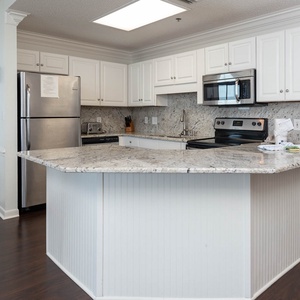 Modern kitchen featuring granite countertops, white cabinetry, and a breakfast bar with seating for casual dining