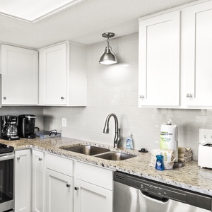 Modern kitchen featuring sleek white cabinetry, granite countertops, Keurig and a coffee maker