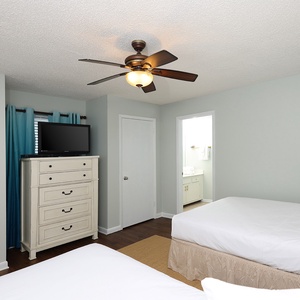 Inviting guest bedroom featuring two double beds, a TV, and easy access to the bathroom for your convenience