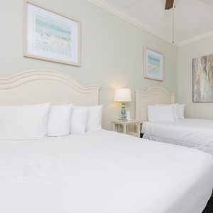 Soothing guest bedroom featuring two comfortable queen beds and coastal artwork, perfect for a relaxing stay