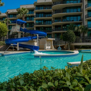 Dive into fun with a thrilling waterslide and outdoor pool, surrounded by lush greenery at Phoenix on the Bay in Orange Beach
