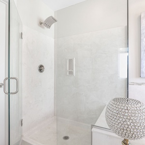 The sleek glass shower features elegant tile and glass work, perfect for a refreshing retreat