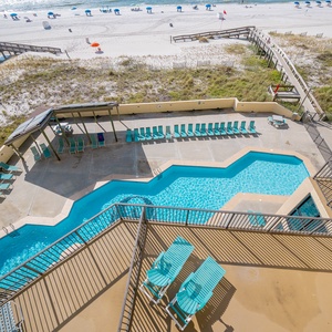 This inviting outdoor area features a sparkling pool, lounge chairs, and easy access to the beautiful beach