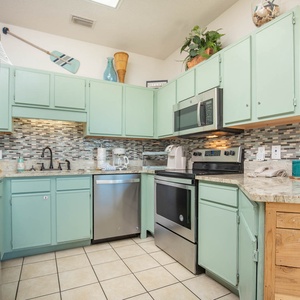 Bright mint green cabinets complement the stylish countertops in this fully-equipped kitchen, perfect for preparing meals