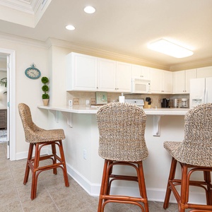 Enjoy casual meals at the breakfast bar with woven stools, overlooking the kitchen and comfortable master bedroom