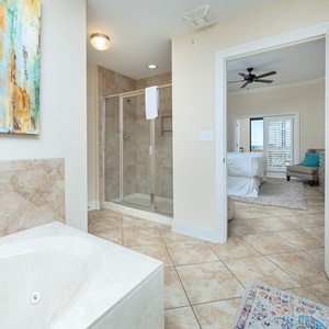 Refreshing master bathroom featuring a jetted tub, walk-in shower, and a view into the master bedroom beyond