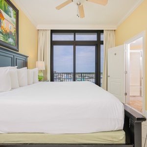 Stylish guest bedroom featuring a plush king bed and balcony doors showcasing a lovely coastal view