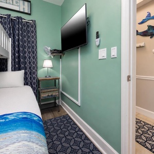 This cozy bedroom features a comfortable bed, a mounted TV, and playful marine decor, perfect for a relaxing stay