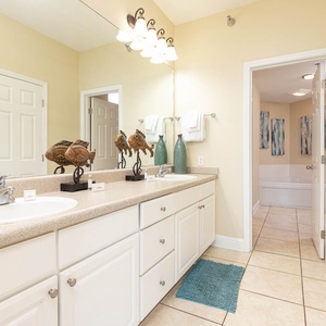 The master bathroom features dual sinks, decorative fish accents, and a relaxing tub area, creating a serene retreat