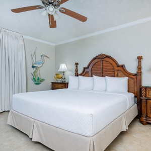The cozy master bedroom features a king bed, elegant furnishings, and beachfront balcony access