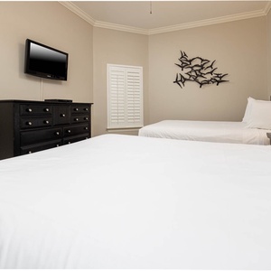 This guest bedroom features two comfortable queen beds, a flat-screen TV, and stylish decor for a relaxing stay