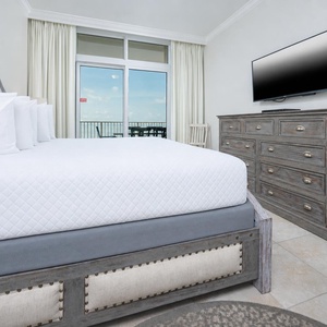 Relax in the master bedroom featuring a king bed, stylish decor, and a beachfront balcony view