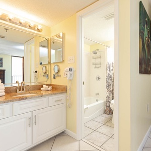 Bright master bathroom featuring a vanity with granite countertops, a tub/shower combo, and decorative mirrors