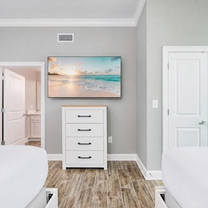 Unwind in this guest bedroom featuring two comfortable queen beds, a stylish dresser, and a large TV