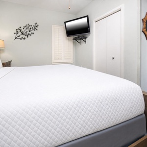 Brightly decorated bedroom featuring a plush king bed, wall-mounted TV, and charming decor for a relaxing getaway