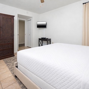 This cozy bedroom features a comfortable bed, a TV for entertainment, and elegant wooden cabinetry for storage