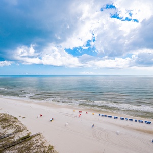 Coastal view with colorful beach umbrellas lining the sandy shore under a vibrant sky