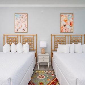Cheerful guest room with two queens, colorful artwork, and stunning beach views