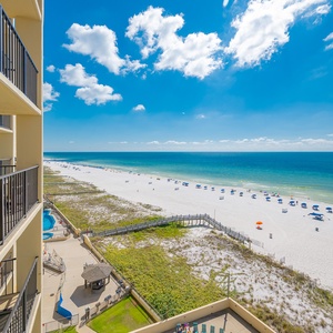 Stunning view of the serene beach and vibrant umbrellas under a bright blue sky from a spacious balcony