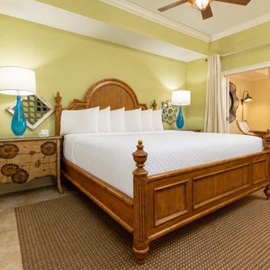 The master bedroom features a charming king bed, bright green walls, and a stylish blue lamp, creating a refreshing retreat