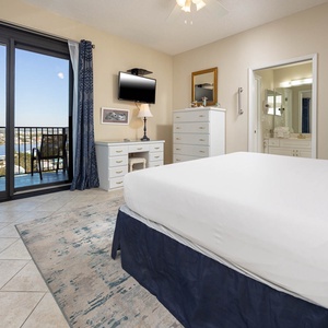 Bright and airy master bedroom featuring a comfortable king bed, a dresser, and a balcony with a scenic view of the water