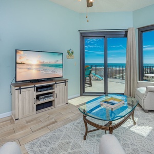 Inviting living area with a large TV and beautiful beach views through sliding glass doors