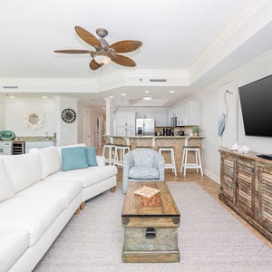 Spacious living space, surrounded by coastal decor and a view of the open kitchen and dining area