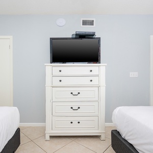 Relax in this comfortable guest room featuring two double beds, a dresser with a TV, and easy access to nearby storage