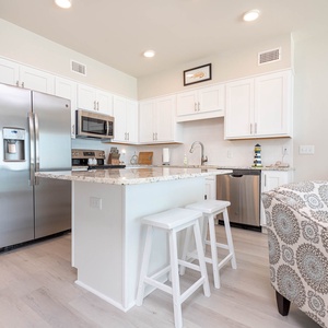 The kitchen features stainless appliances, granite countertops, a spacious island, and cozy seating area for casual dining