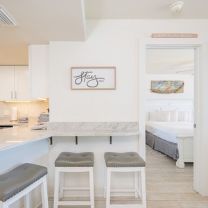 A sleek breakfast bar with gray stools complements the modern kitchen, featuring a marble countertop and stylish decor