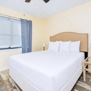 Sunlight filters through blinds on the queen bed in the master suite for a calm retreat feel