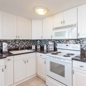 This kitchen features sleek white cabinetry, granite countertops, and a stylish backsplash, perfect for preparing meals