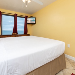 Master bedroom featuring a plush king bed and a large window with a beautiful beach view of the tranquil waters