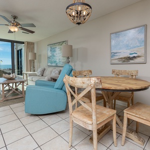 Relax in the inviting living area with a beach view, featuring cozy seating and a rustic dining table for meals together
