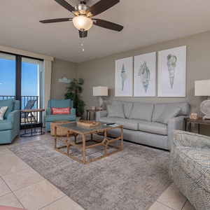 Cozy living area features a light gray sofa with queen sleeper, vibrant accent chairs, and a balcony with a beautiful view