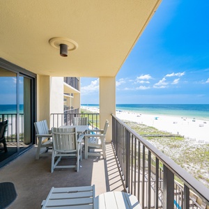 The balcony features a dining set with beach views, showcasing the inviting coastline and vibrant blue waters