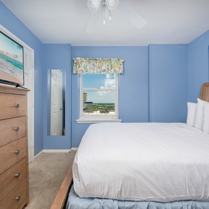 The guest bedroom features a large bed, a TV, and a bright window with a lovely view of the surroundings