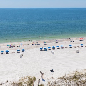 Vibrant umbrellas shade beachgoers on a pristine stretch of white sand, inviting relaxation and fun by the tranquil waters