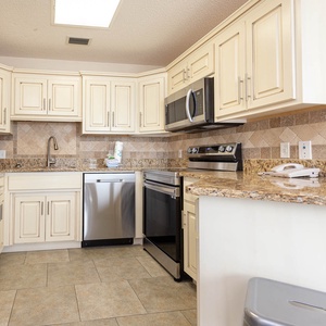 Bright kitchen features cream-colored cabinetry, granite countertops, and stainless appliances, perfect for preparing meals