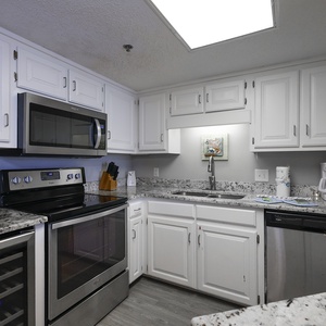 Bright white cabinetry complements the marbled countertops in this kitchen featuring a wine cooler, coffee maker and Keurig
