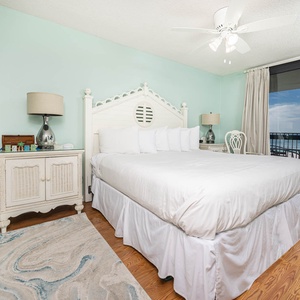 Master bedroom featuring a king bed, elegant nightstands, and a view of the balcony overlooking the gulf