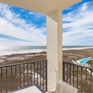 Expansive beach front view showcases the shimmering gulf and the inviting pool area from the balcony's comfortable seating