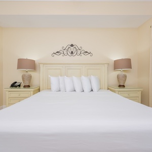 Master suite featuring a king bed, stylish lamps, and coastal artwork for a relaxing getaway